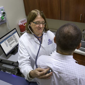 Nancy Klimas, M.D., co-principal investigator and director of Nova Southeastern University’s College of Osteopathic Medicine’s Institute for Neuro Immune Medicine, checks a patient’s vital signs.