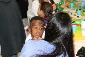 : A young boy waiting to be seen at the dental clinic at Nova Southeastern University's College of Dental Medicine gets his face painted. The face-painting was part of the school's national kickoff event for Give Kids A Smile, Feb. 5.